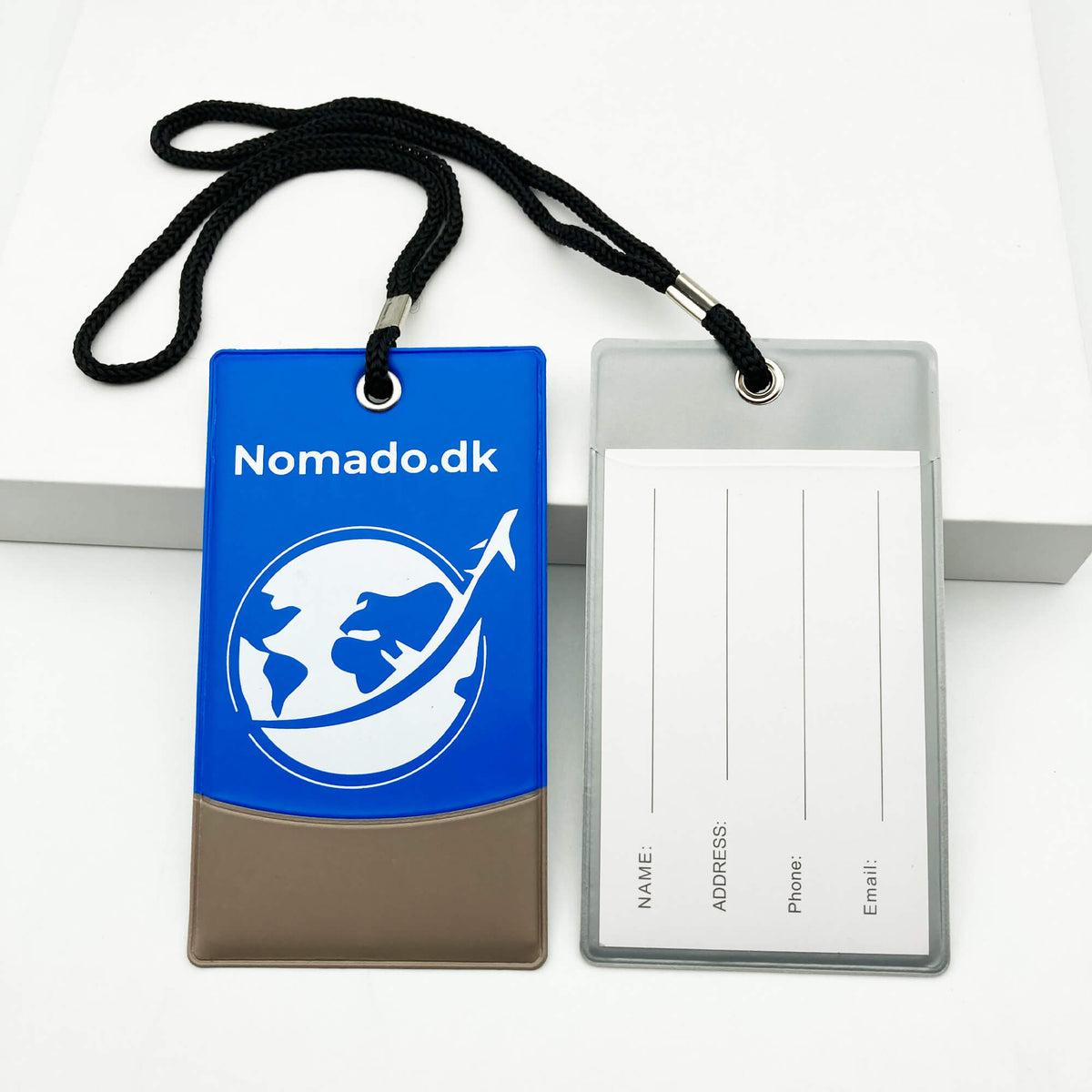 Blue luggage tag with the Nomado logo and a grey tag for contact information